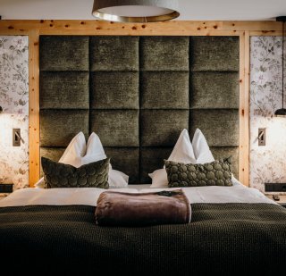 Rieser - Zimmer Betthaupt in grün mit Absteppungen, Zierkissen in grünem Velours mit geometrischem Muster, Tagesdecke grün